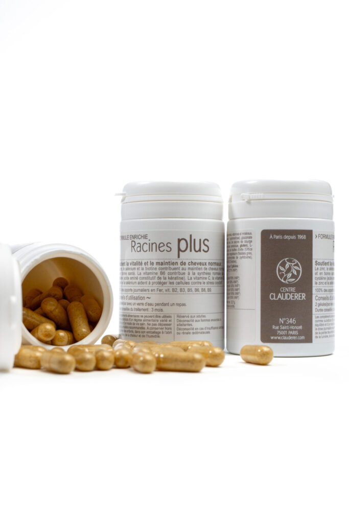 Three boxes of CLauderer’s Racines Plus hair growth supplements. One has been knocked over and you can see the capsules